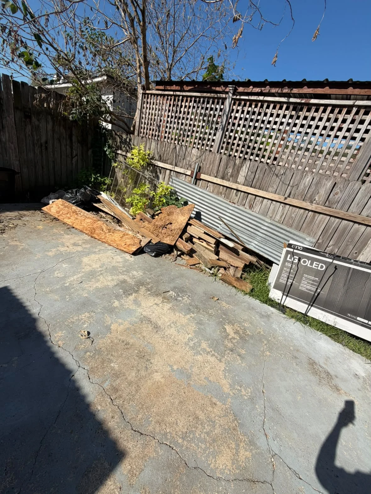 Wood and debris along a backyard fence before removal