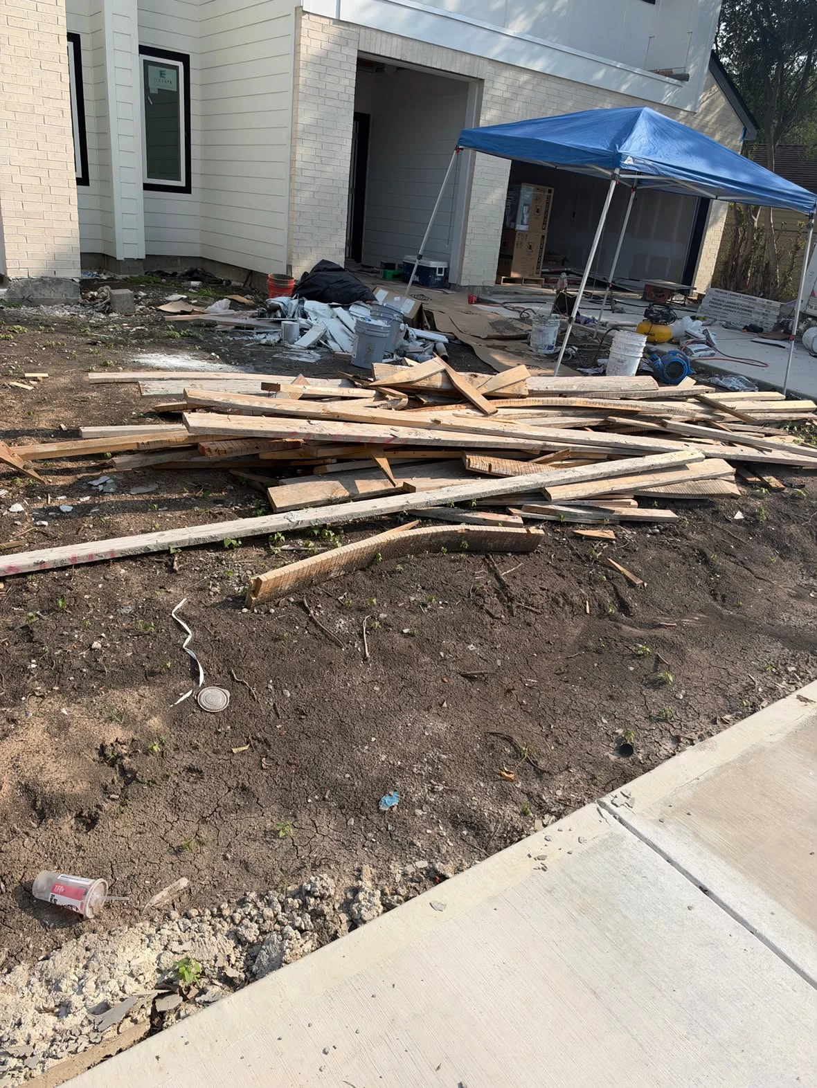Lumber and construction debris beside a house before pickup
